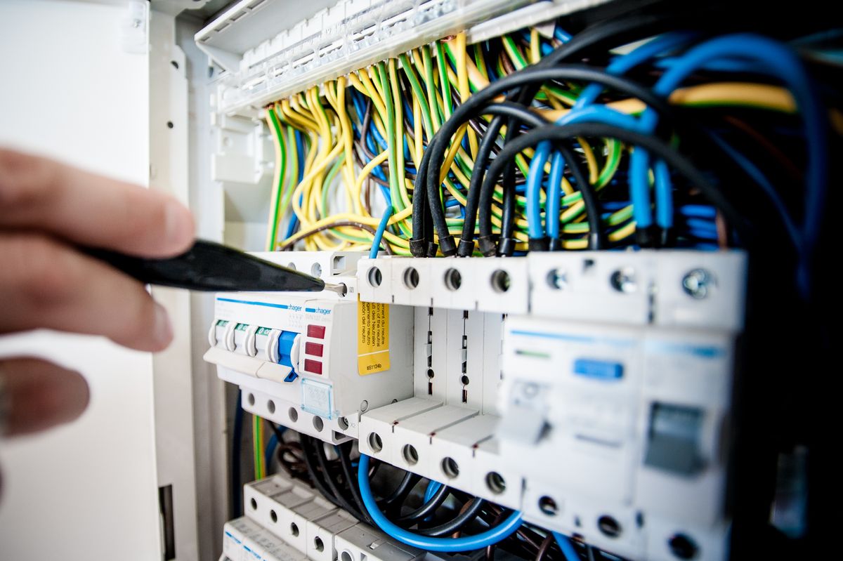 Electrician testing wired circuit breakers in a distribution board