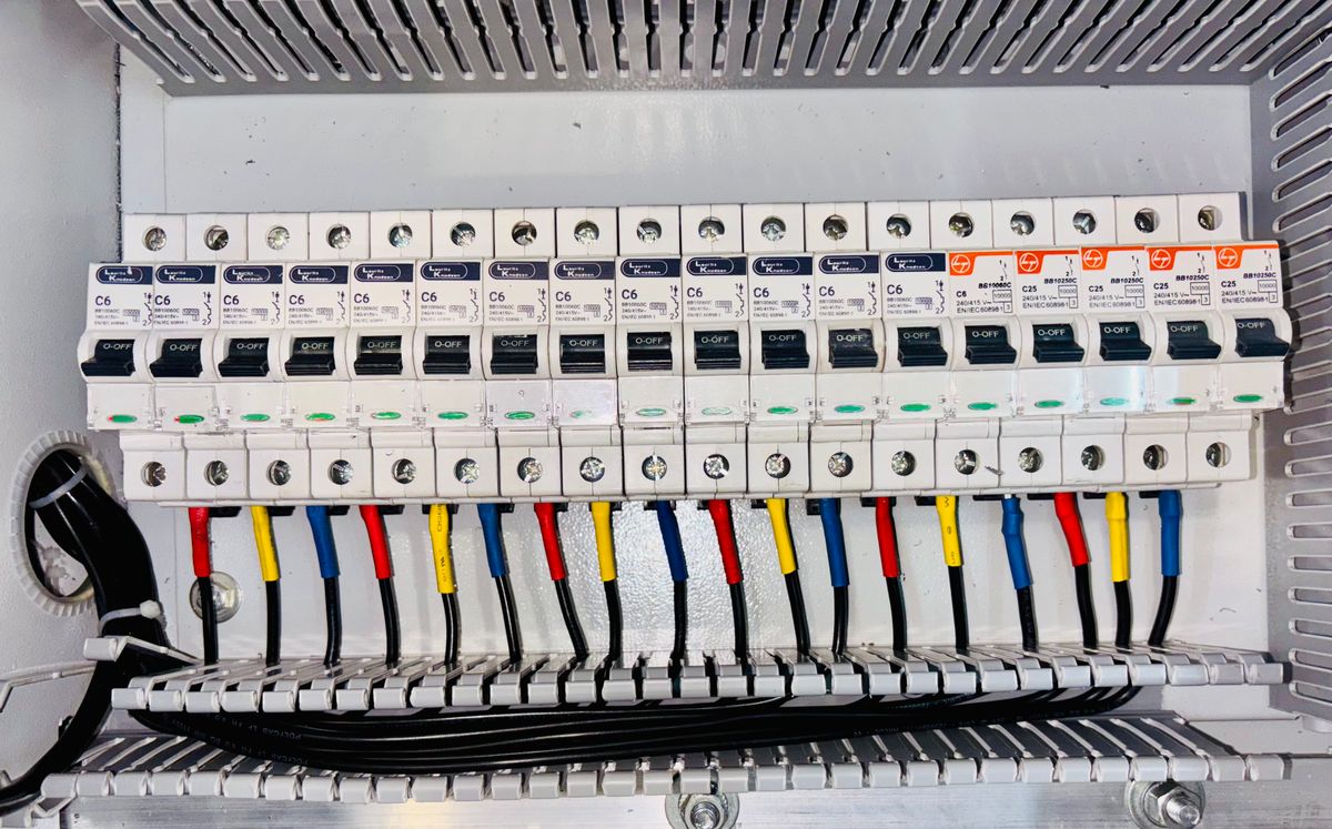 Row of circuit breakers with neat color-coded wiring in a distribution panel