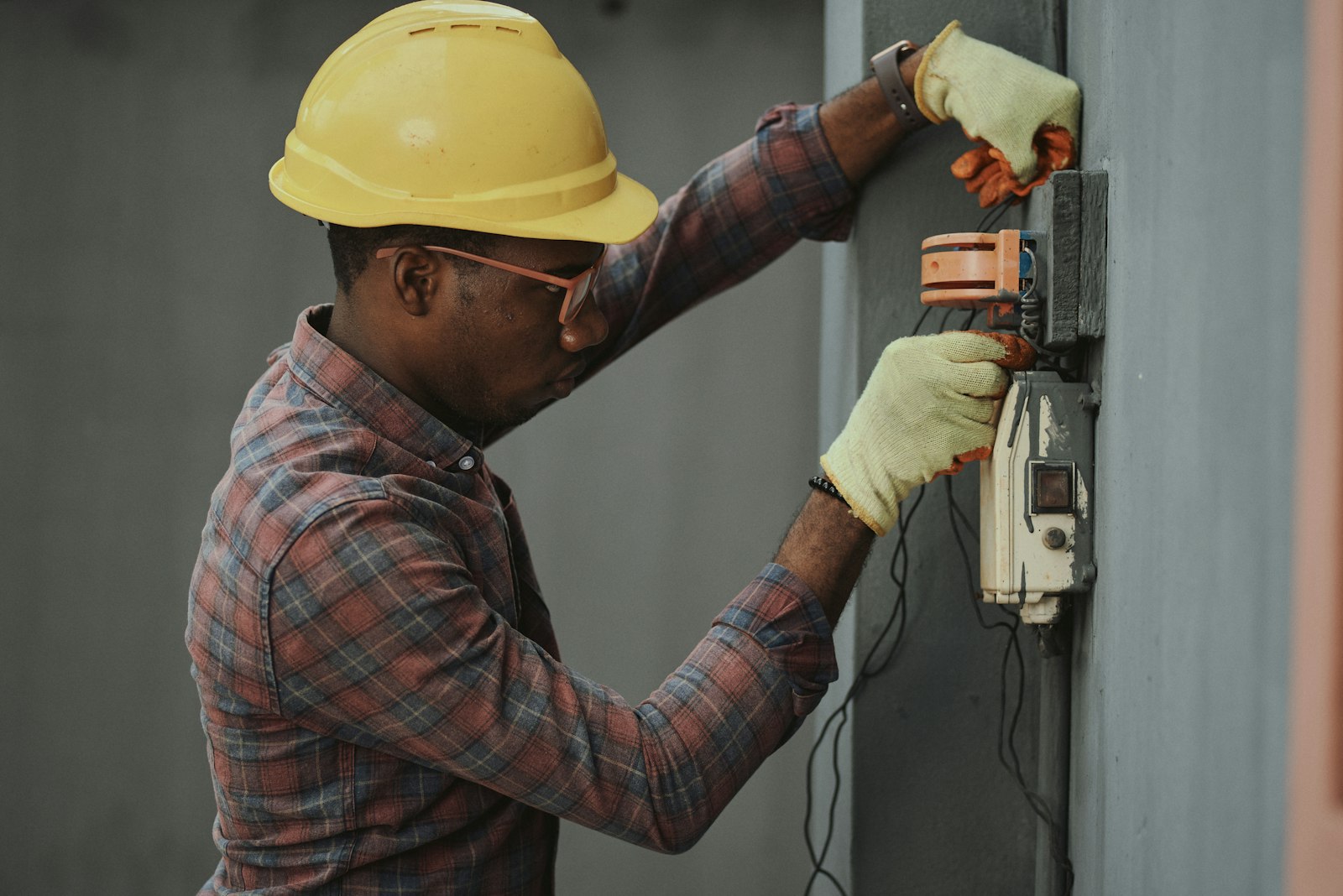 Electrician in a hard hat wiring an electrical installation